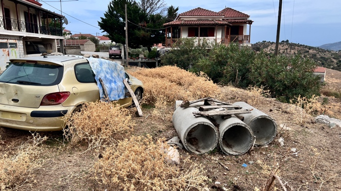 A car parked in a field with a house in the background

Description automatically generated