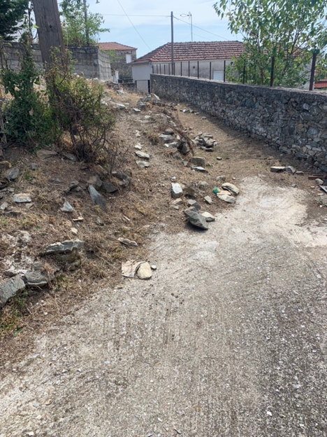 A dirt road with rocks and a stone wall

Description automatically generated